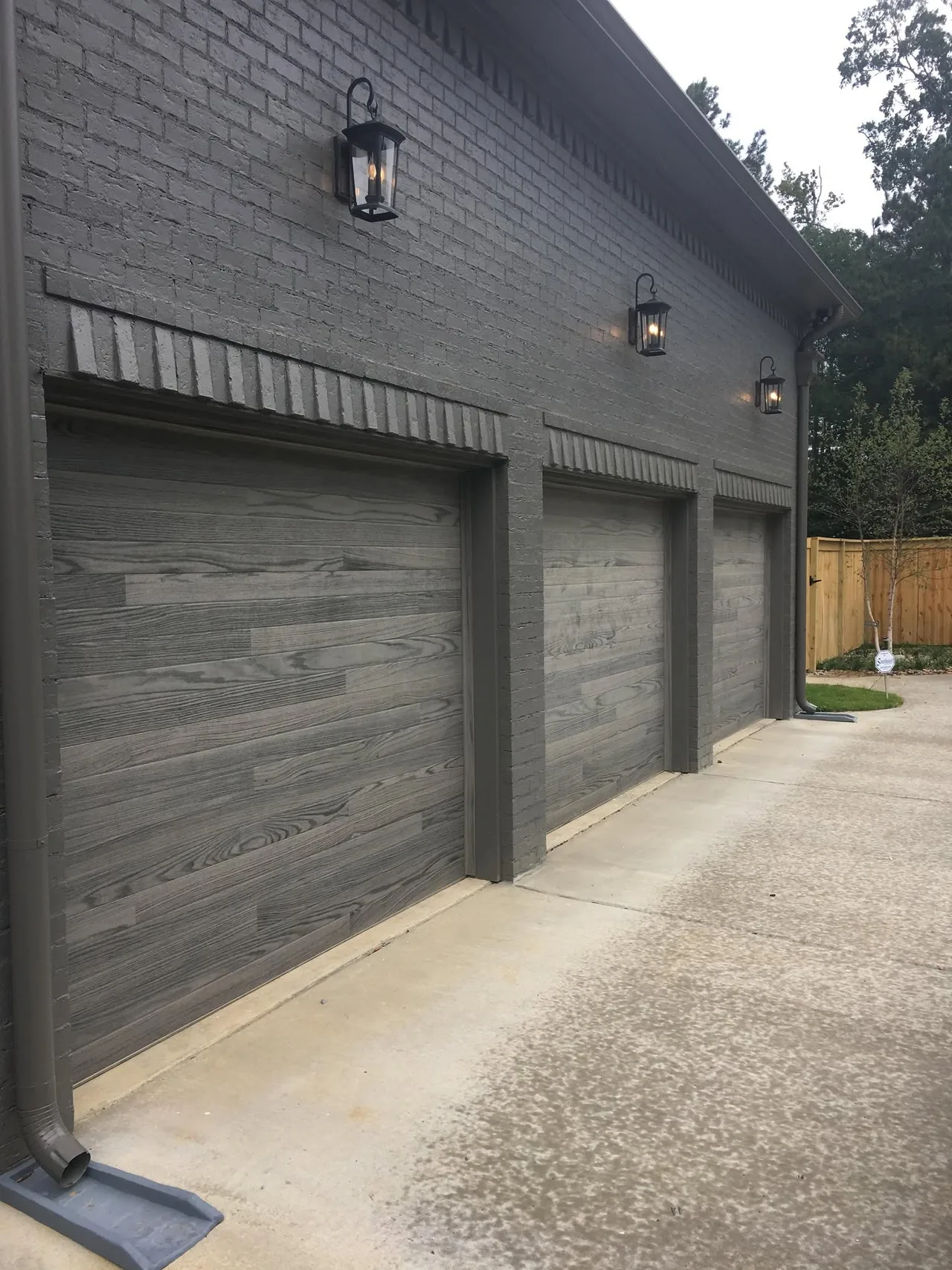 Three gray doors on dark brick